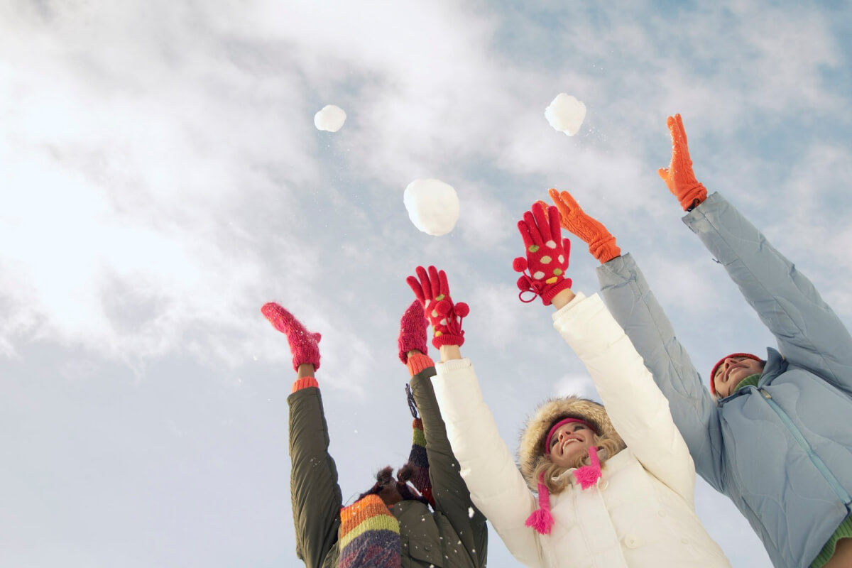 happy women throwing snow into the air enjoying winter