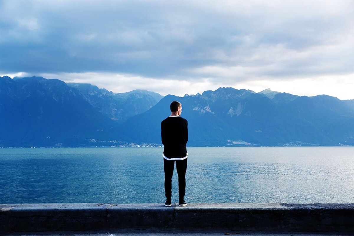 man standing on the beach looking at mountains