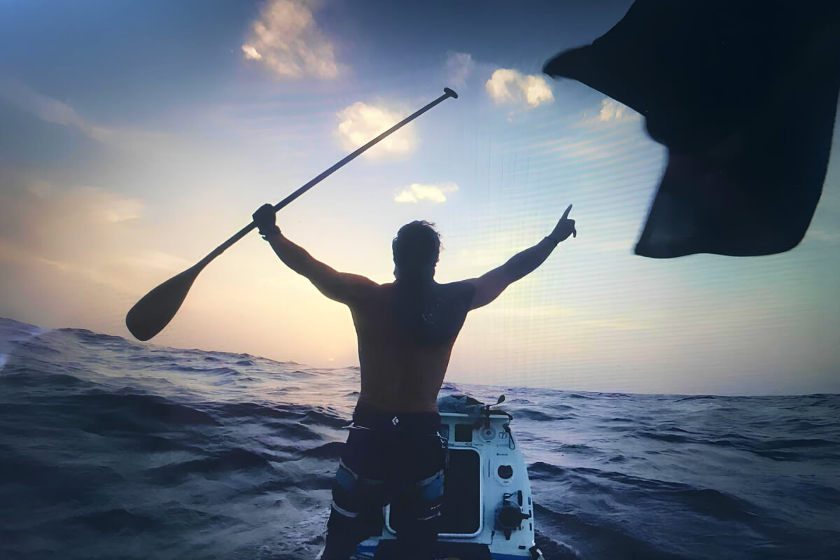 man on a paddle boat with hands up in air