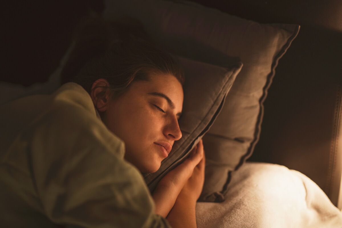 Lamp illuminating sleeping young woman at night