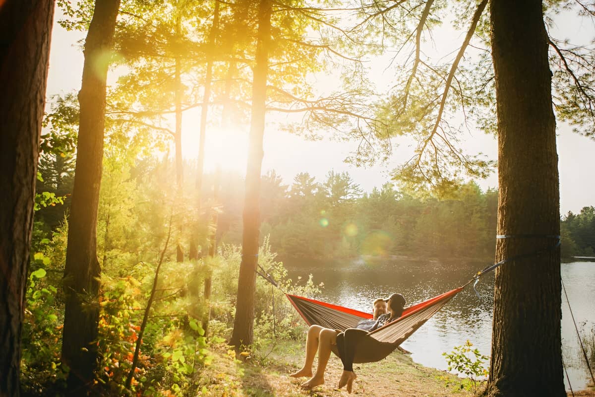 Woman and man sitting in a hammock next to a river