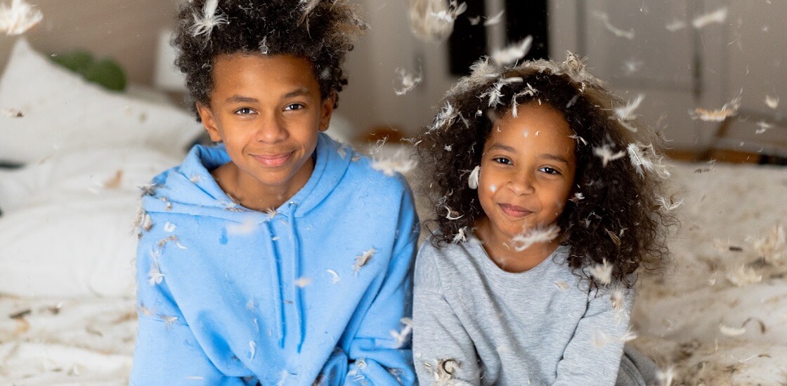 African american son and daughter drizzled in pillow stuffing after pillow fight