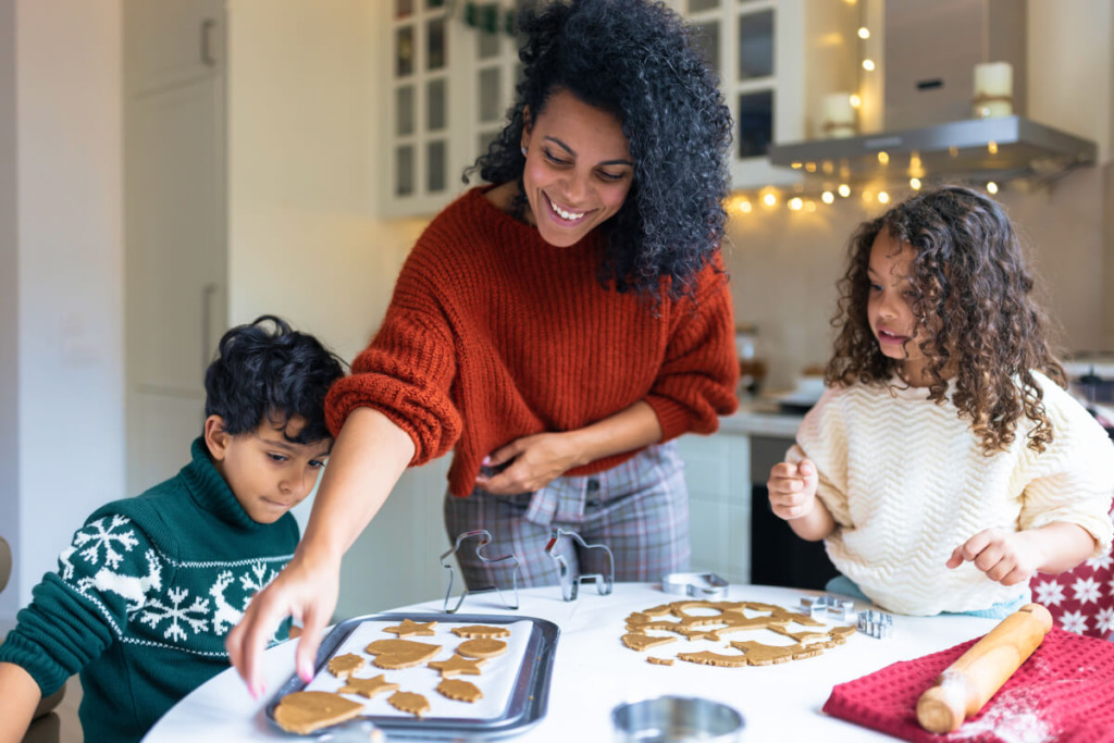 Sister and brother making winter holiday gingerbread cookies with a mother