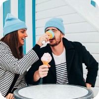 Woman playfully putting ice cream cone on mans nose and man holding ice cream cone
