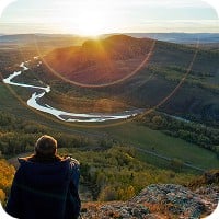 Person sitting on hill looking at nature