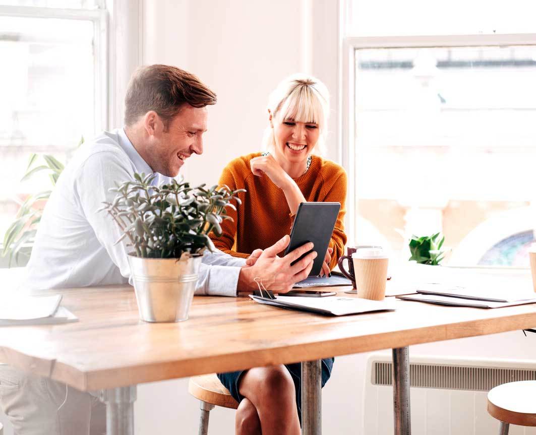 Woman and man looking at a tablet and laughing