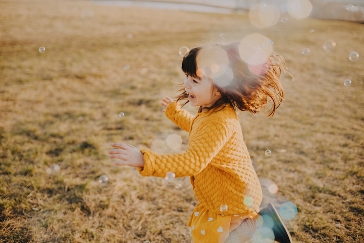 Young girl playing with bubbles and laughing