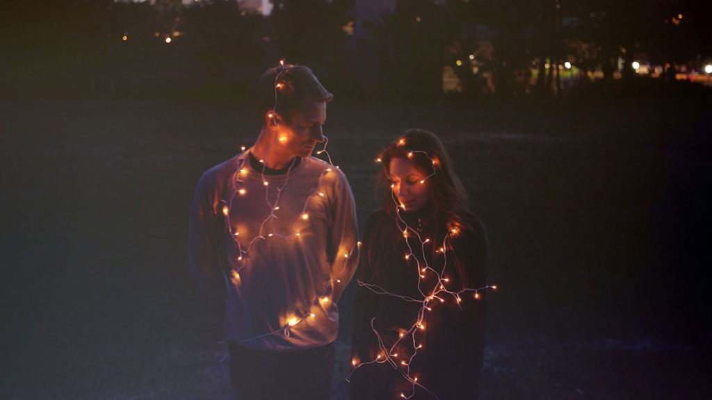 Woman and man wrapped in fairy lights