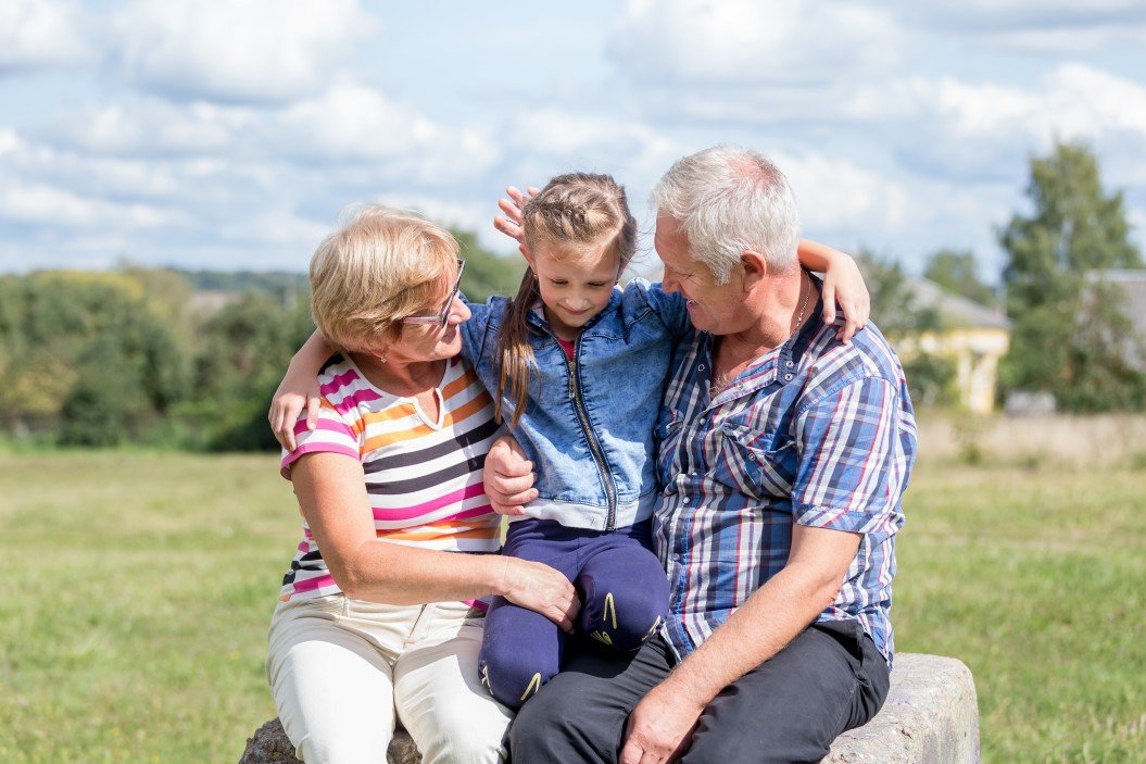 Grandparents sitting with granddaughter outside