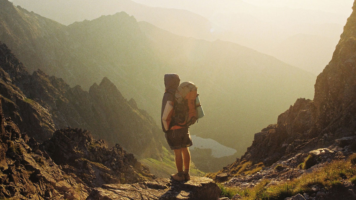 Man with hiking bag looking at the view of the mountains