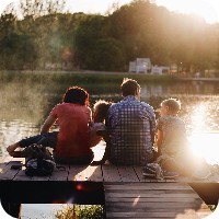 Family sitting on dock near a lake