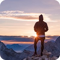 Man on top of mountain looking at the sunrise