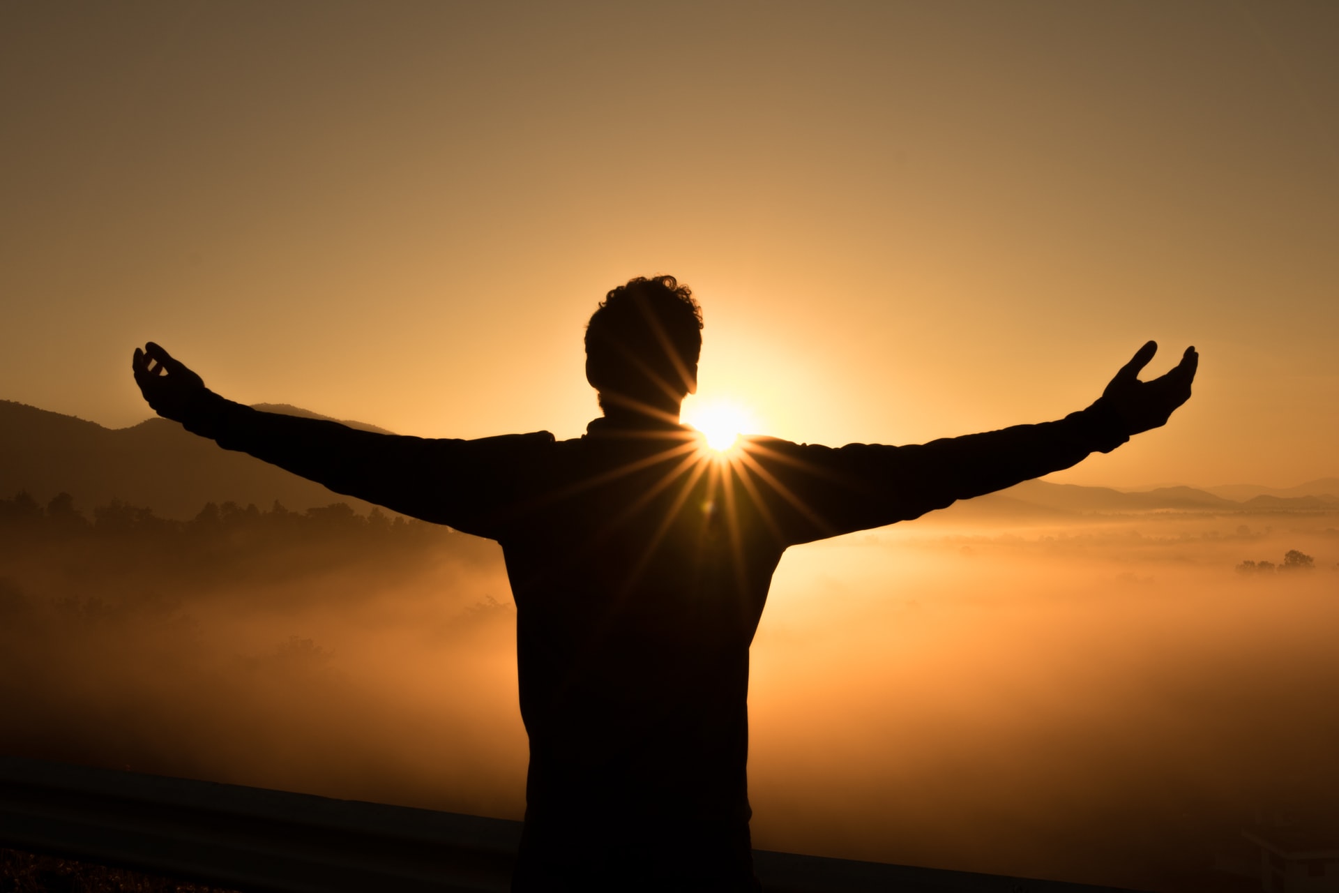 Man with arms raised up during a sunset