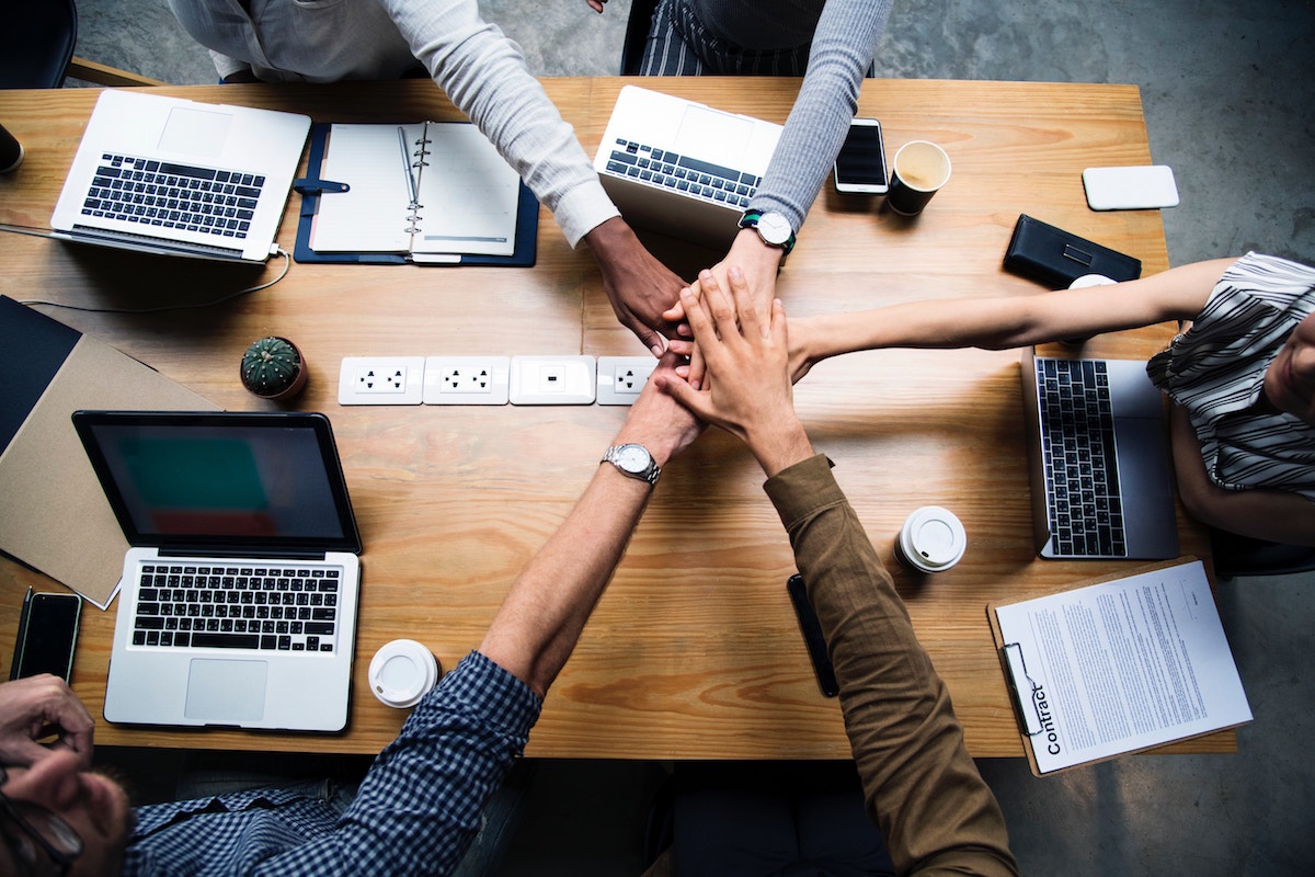 Employees stacking hands on top of each over over work desk