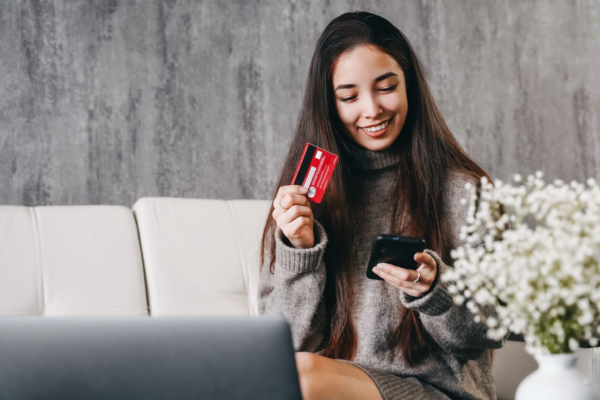 Asian woman makes online purchases over the internet using a laptop and a bank card