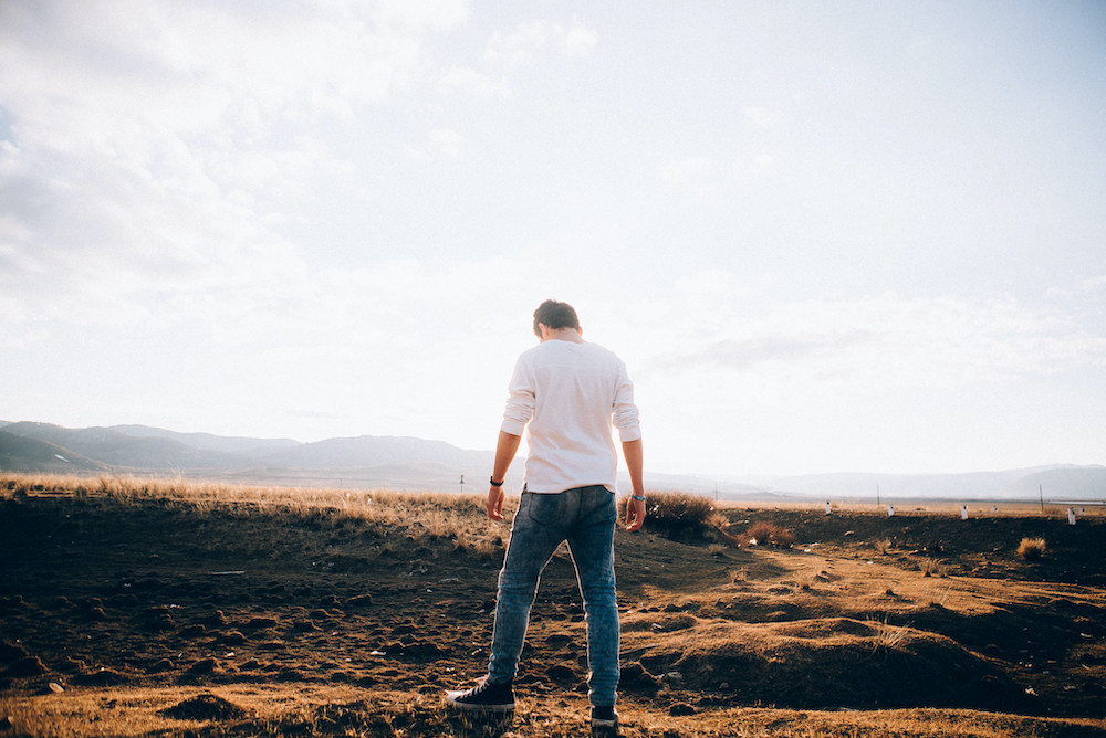 Man looking down off a mound of dirt