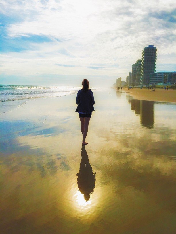 Woman walking on the beach with skyscrapers in the background