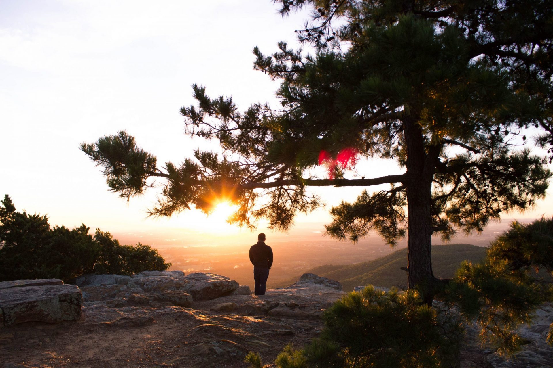 man standing on a mountain looking at sunset