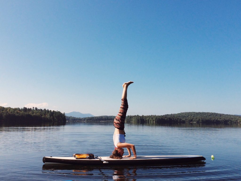 Woman doing yoga on surf board on a lake