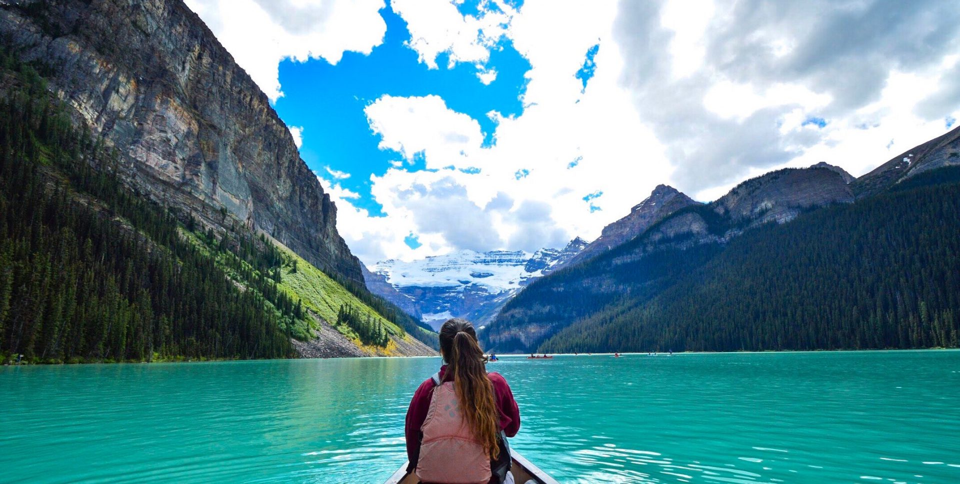 Woman in kayak on a clear blue lake near mountains