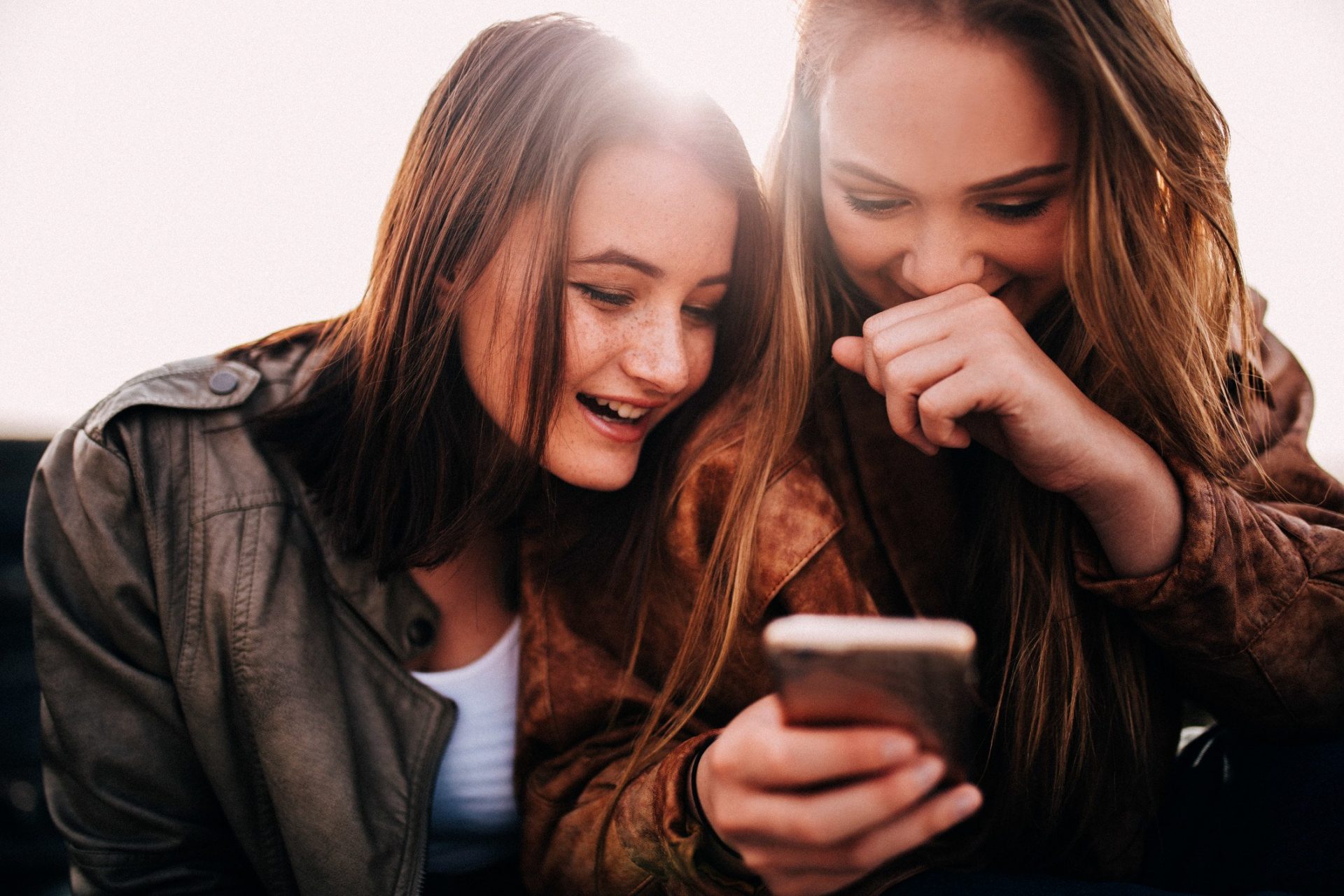 teenage girls looking at funny photos on smartphone and laughing t20 g8VNKb