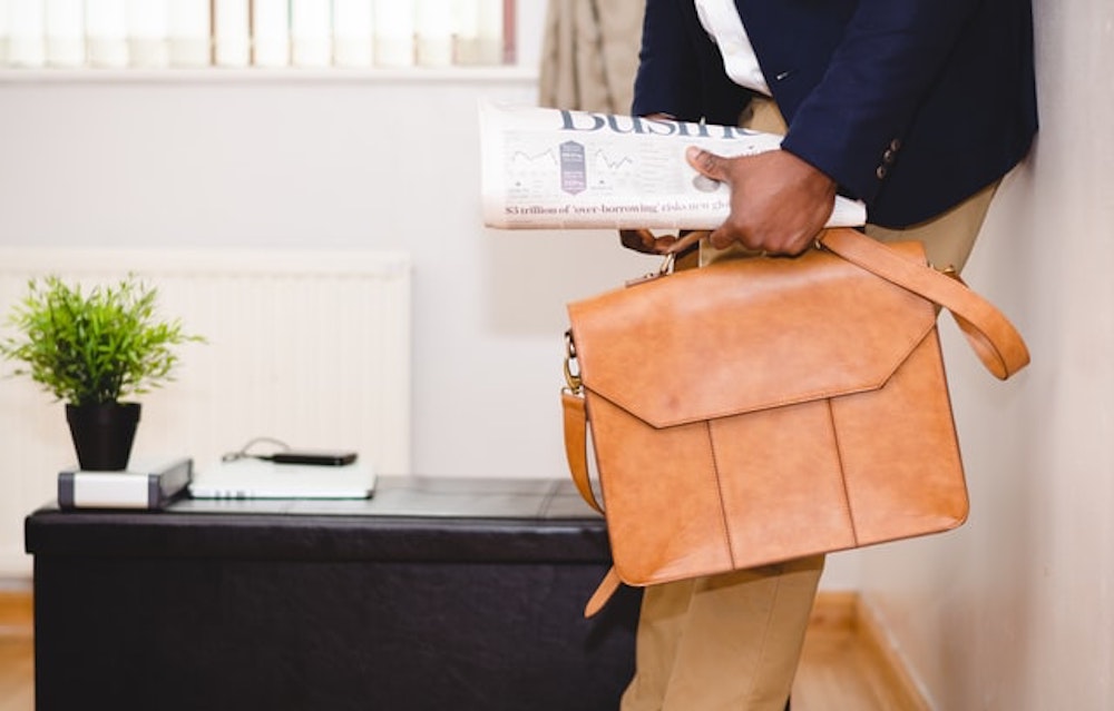 Man holding news paper and briefcase at home