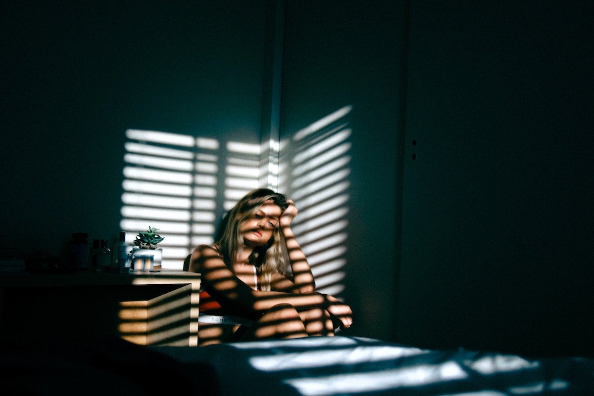 Woman sitting in a corner of dark room looking sad