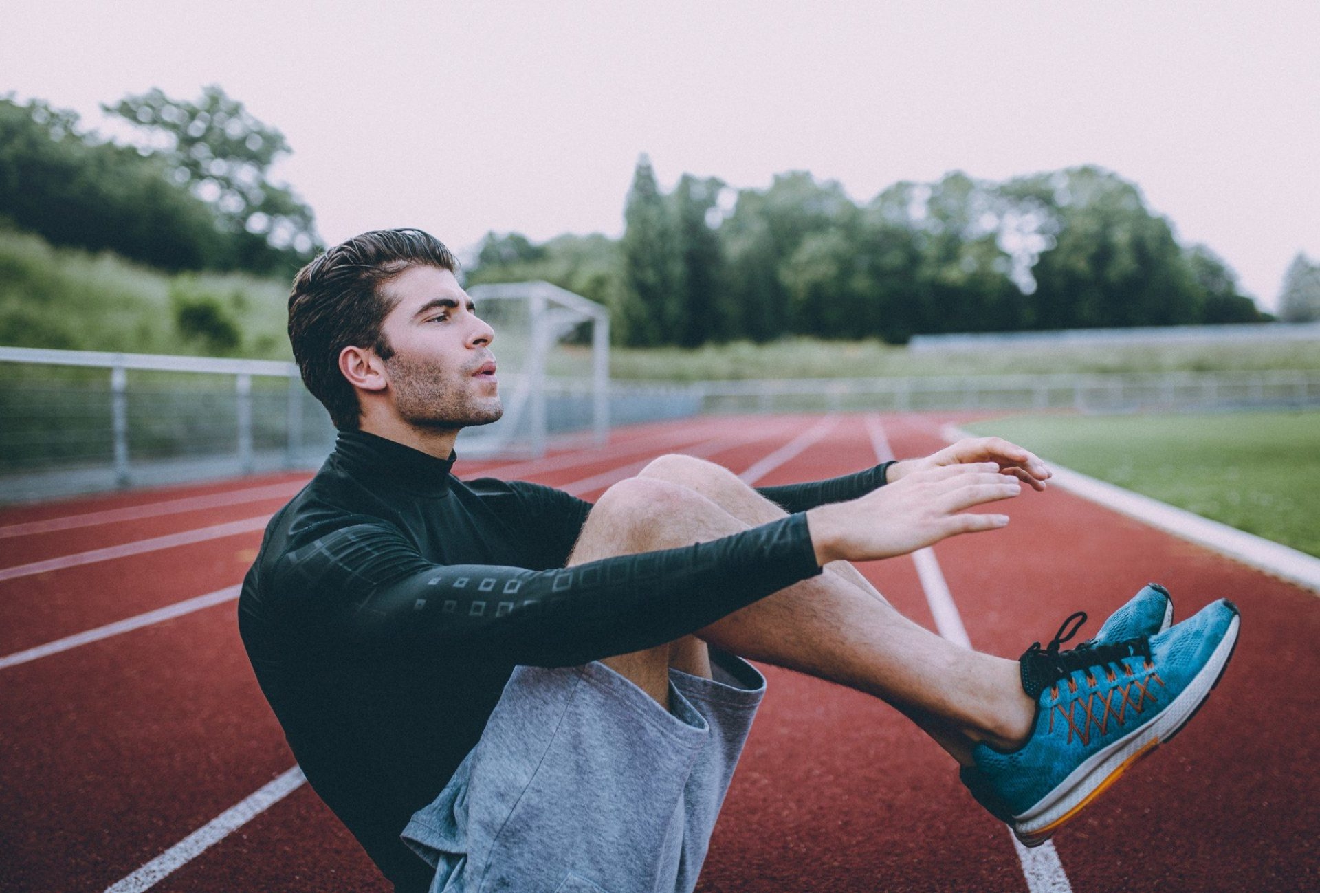 Young sports athlete man doing crunches on sports track