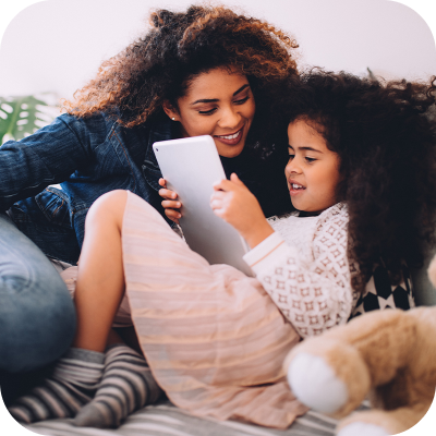 Mother smiling at daughter using tablet
