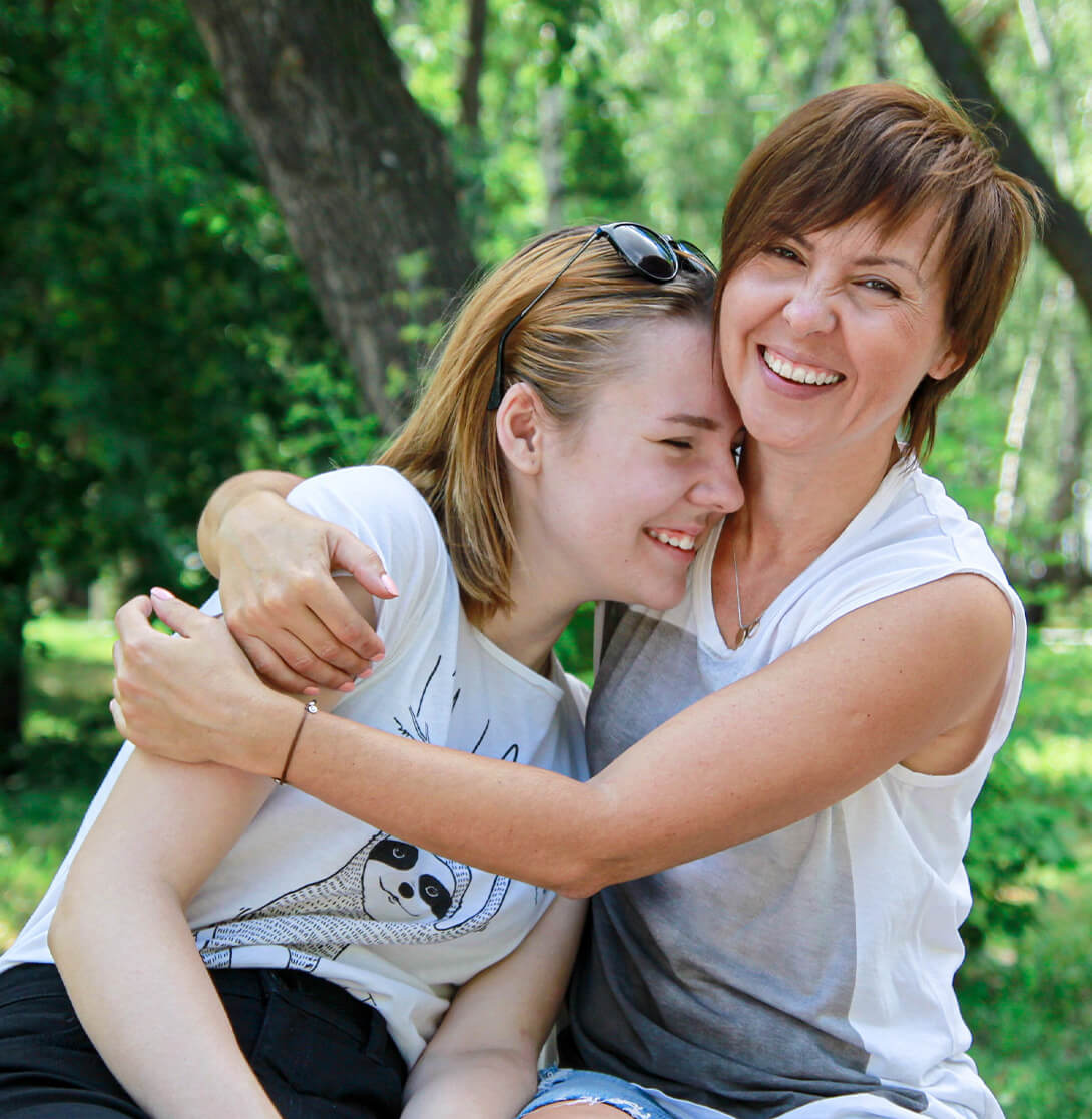 Mother hugging daughter and smiling outside