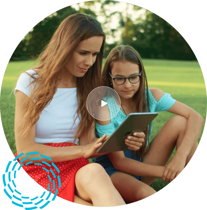 Mother and daughter sitting on grass looking at Ipad