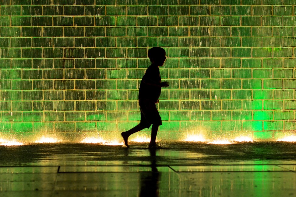 Boy running next to green water fountain