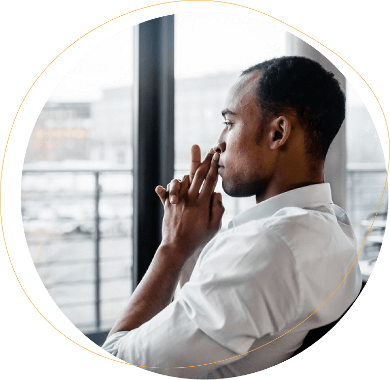 African American man thinking while looking out window with hands on chin