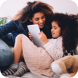 Mother smiling at daughter using tablet