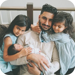 Father surrounded by his children sitting on couch