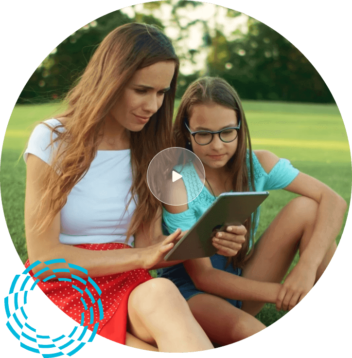 Mother and daughter sitting on grass looking at iPad