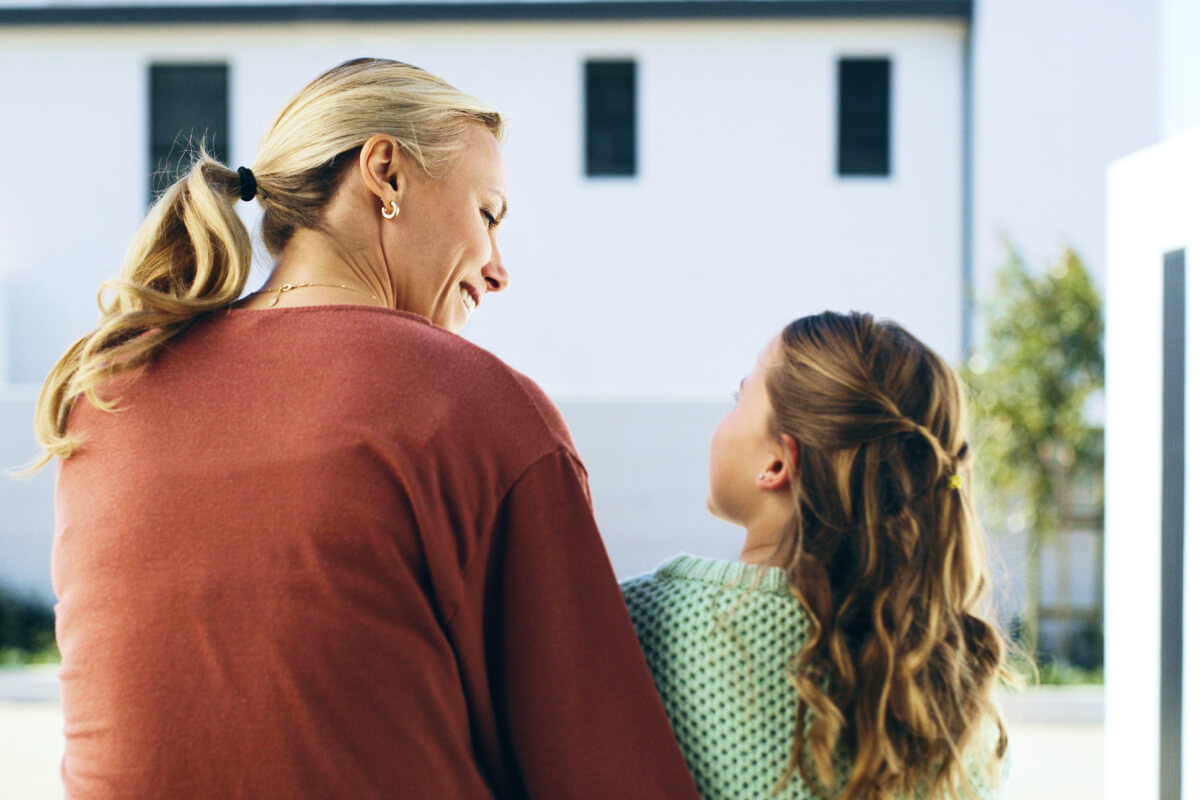 View from behind of happy mother and child talking on outdoor patio