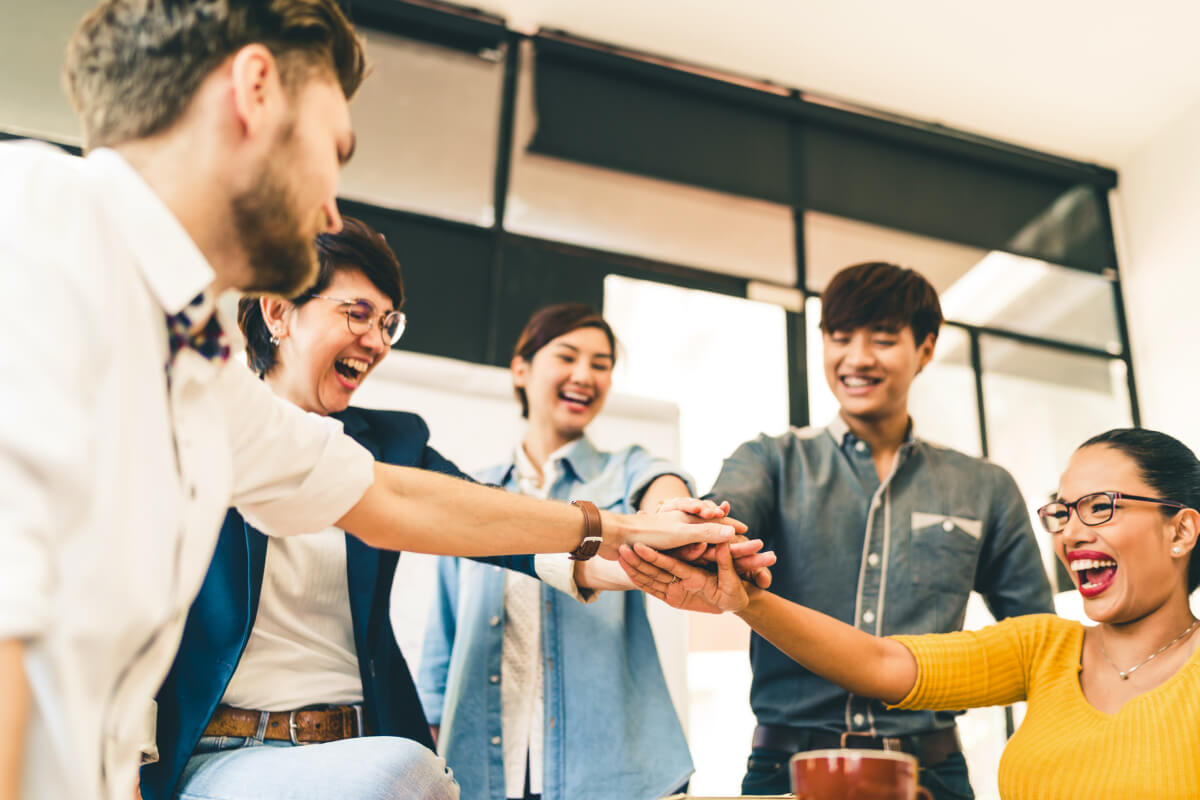 Group of neurodiverse office workers with hands joined together