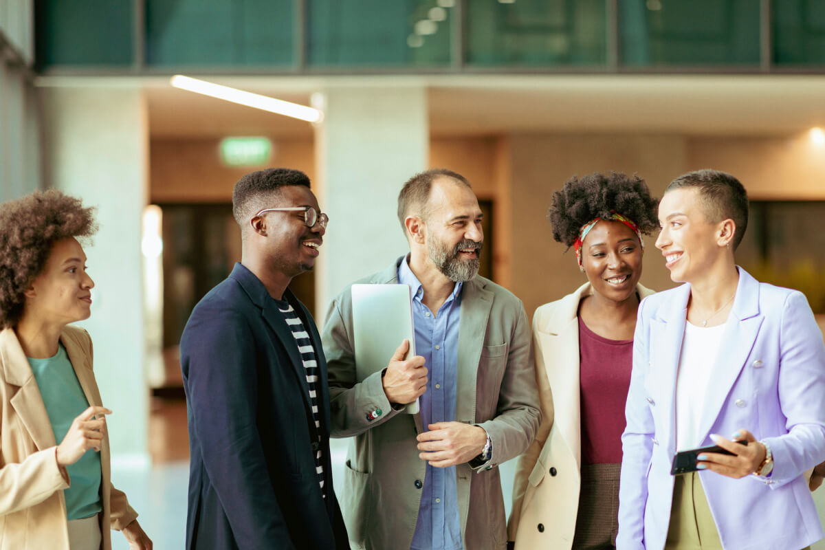 group of diverse coworkers standing at the office corridor and smiling