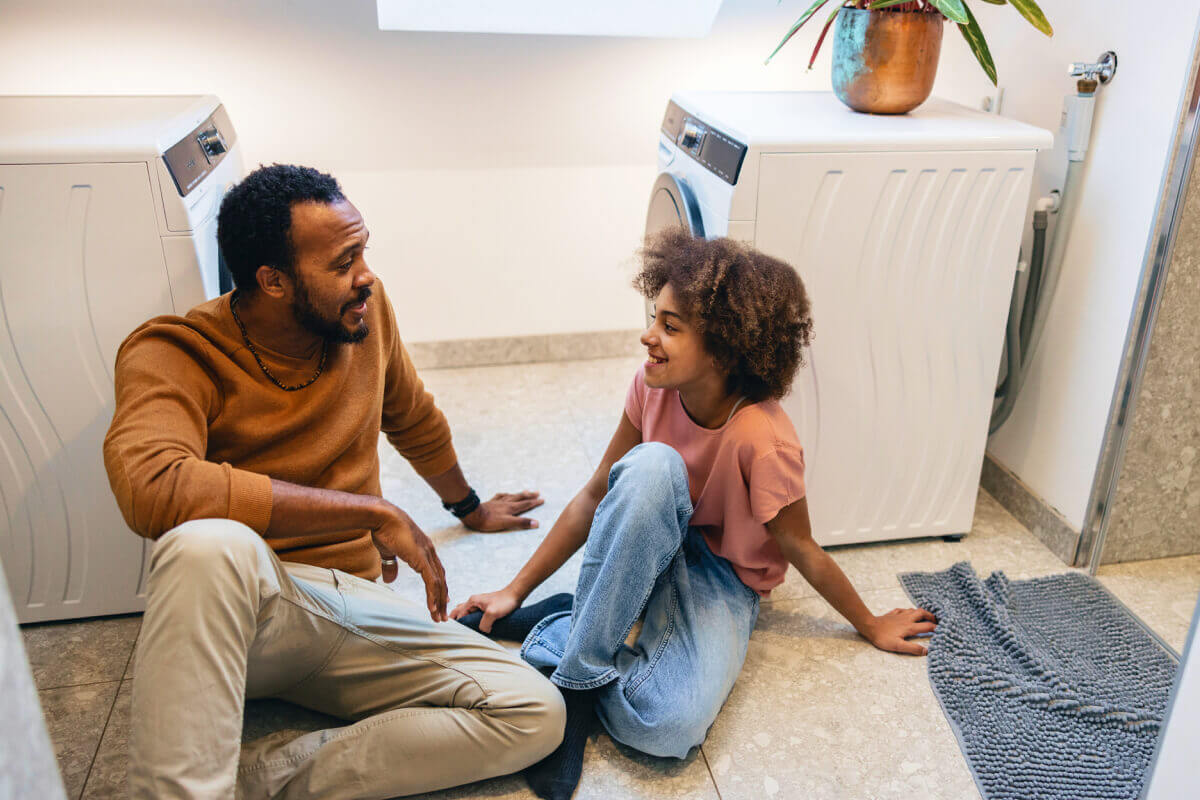 father and daughter on laundry room floor discussing her disability