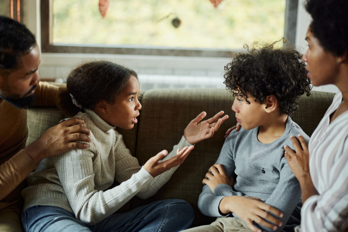 African American kids having communication problems next to parents on sofa