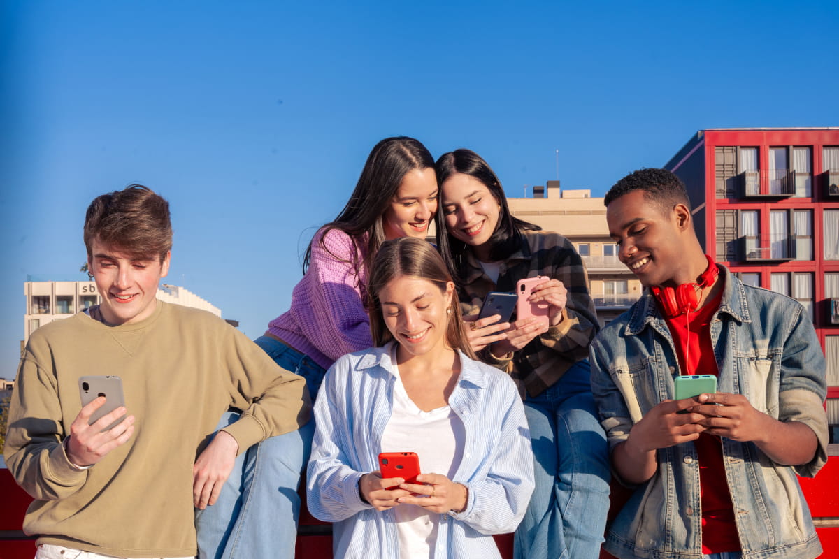 Teenage friends using looking at their smartphones on campus