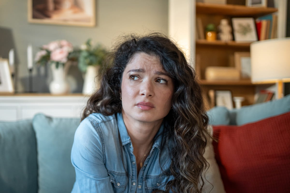 Worried young mother looking away while on sofa