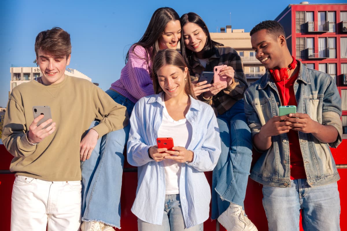 Diverse group of friends looking at phones on campus