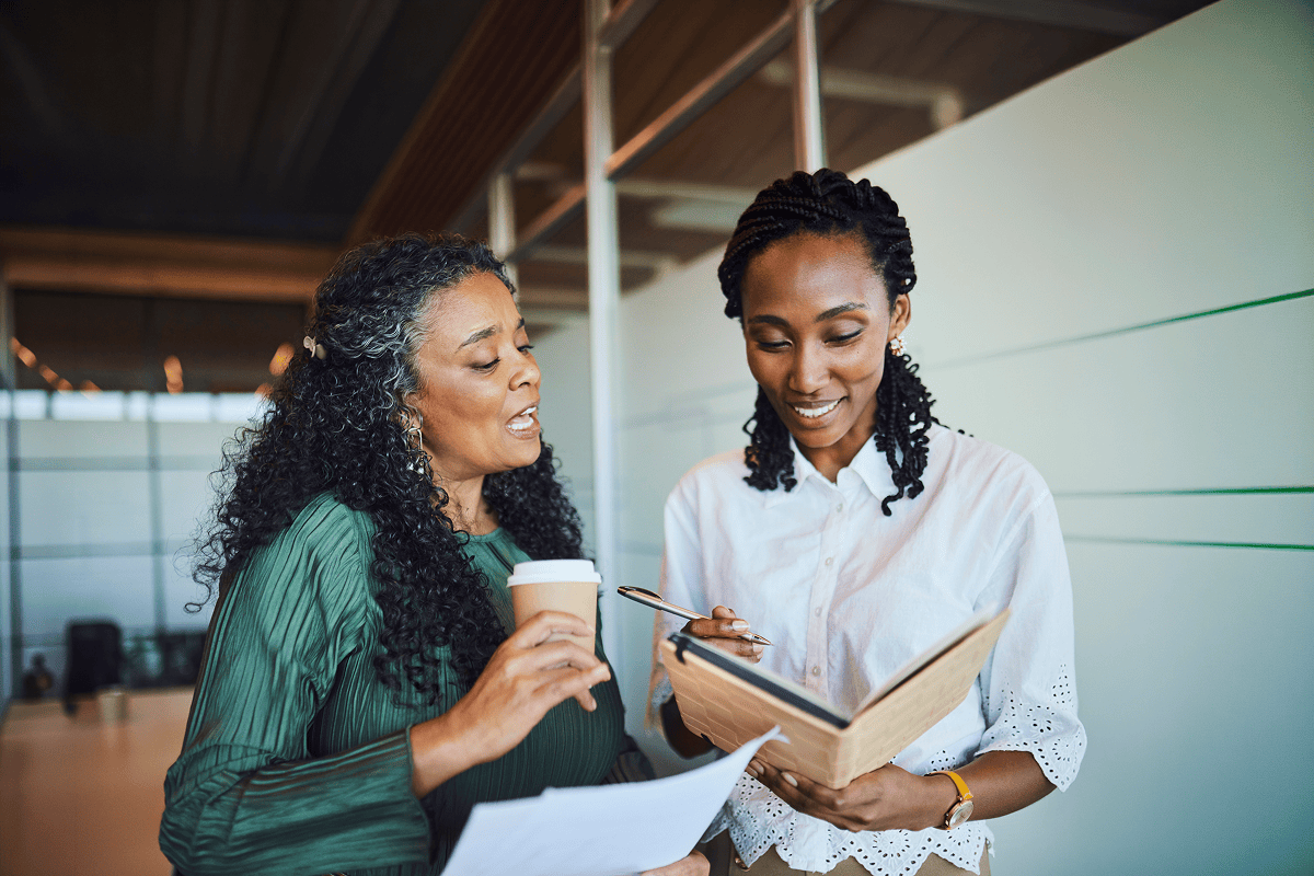 Two women collaborating, reviewing notes and smiling